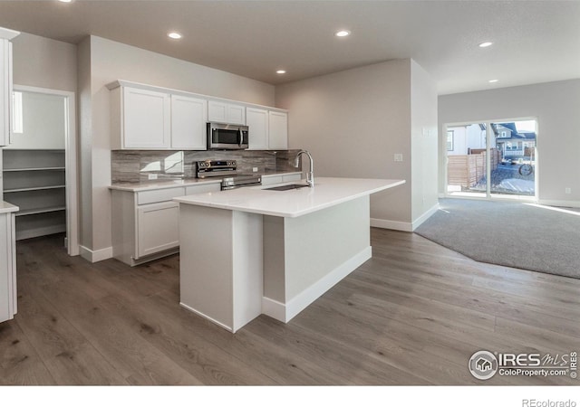 kitchen with sink, white cabinetry, an island with sink, stainless steel appliances, and backsplash