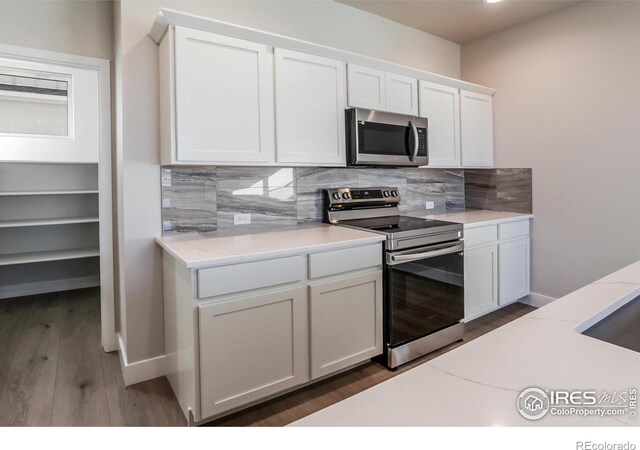 kitchen with stainless steel appliances, white cabinetry, and backsplash