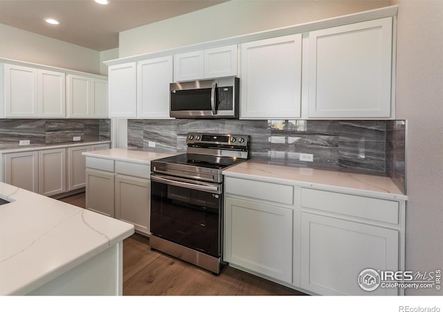 kitchen with stainless steel appliances, dark hardwood / wood-style floors, white cabinets, and backsplash