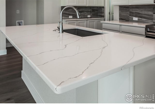 kitchen with light stone countertops, sink, dark hardwood / wood-style floors, and decorative backsplash