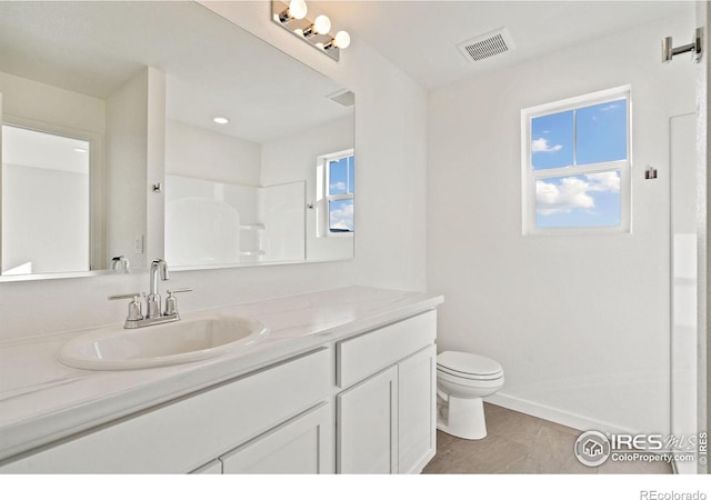 bathroom featuring tile patterned floors, toilet, vanity, and walk in shower