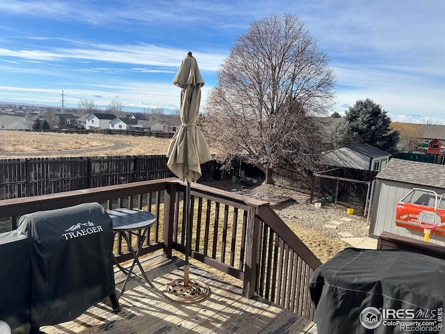 wooden deck featuring a grill and a storage shed