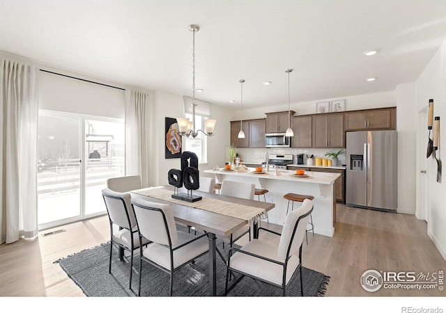 dining area with light hardwood / wood-style flooring and a notable chandelier