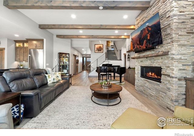 living room with light hardwood / wood-style floors, beamed ceiling, and a fireplace