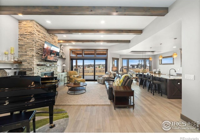 living room with a fireplace, sink, and light hardwood / wood-style flooring