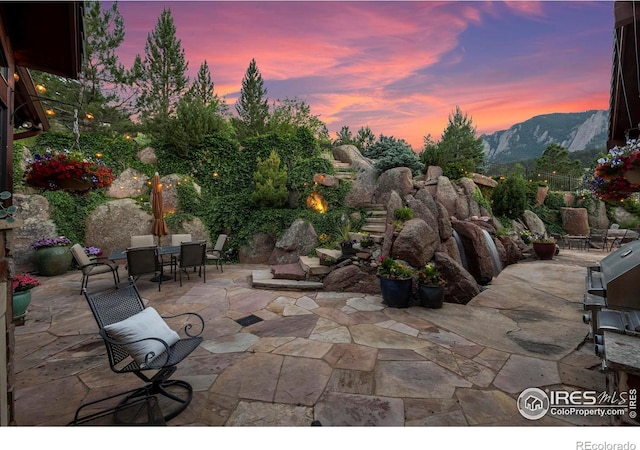 patio terrace at dusk featuring a mountain view