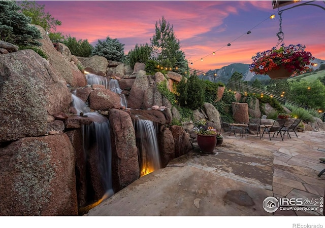 patio terrace at dusk featuring a mountain view