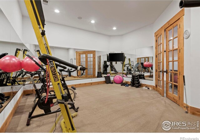 workout room featuring a towering ceiling, light colored carpet, and french doors