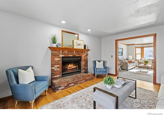 living room with hardwood / wood-style flooring, a brick fireplace, and a textured ceiling