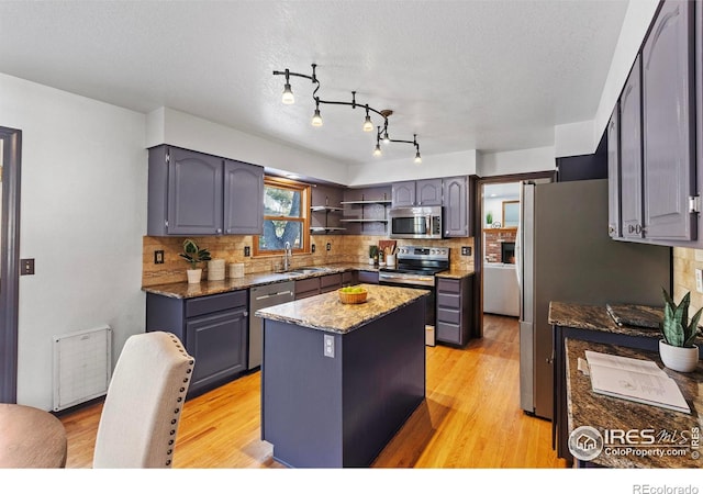 kitchen with sink, stainless steel appliances, tasteful backsplash, a kitchen island, and dark stone counters