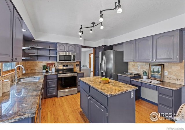 kitchen featuring appliances with stainless steel finishes, sink, a kitchen island, and dark stone counters