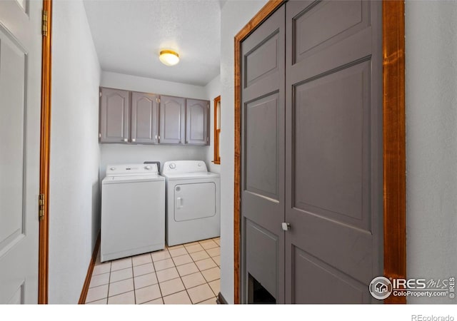 laundry area featuring light tile patterned flooring, cabinets, washer and clothes dryer, and a textured ceiling