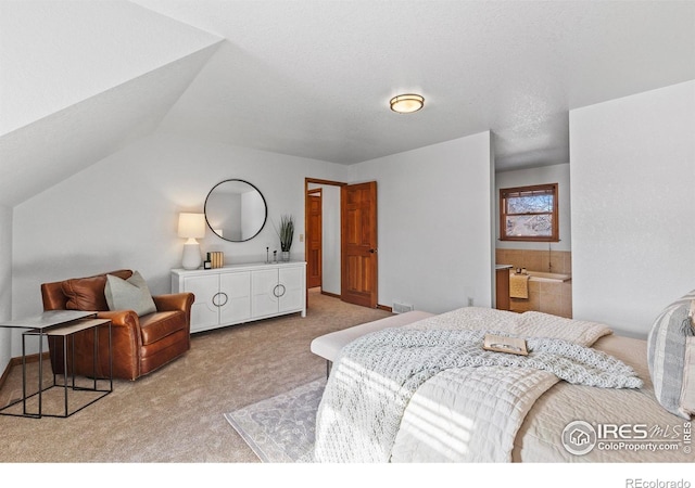 bedroom with light carpet, ensuite bath, and vaulted ceiling