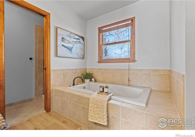 bathroom featuring hardwood / wood-style floors and a relaxing tiled tub