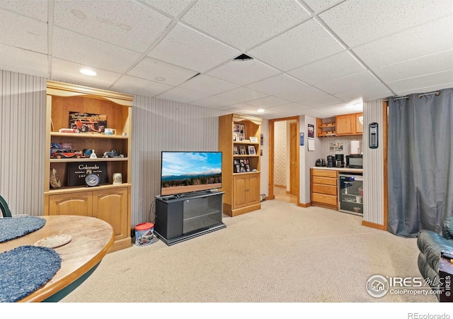 carpeted living room featuring wine cooler, a paneled ceiling, and bar area