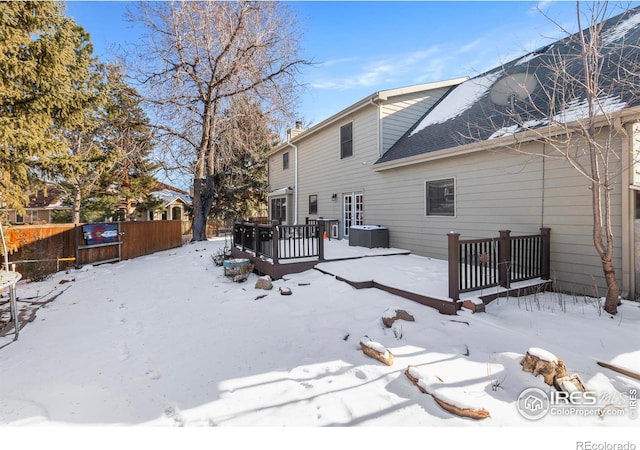 snow covered back of property featuring a wooden deck