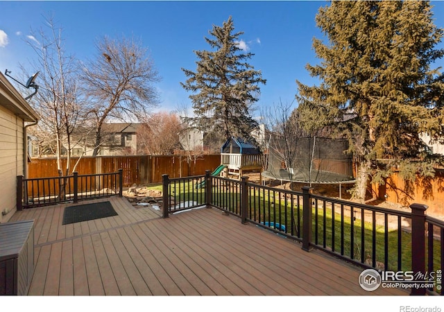 wooden deck with a trampoline, a lawn, and a playground