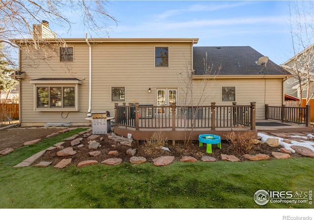 back of property featuring a wooden deck and a lawn