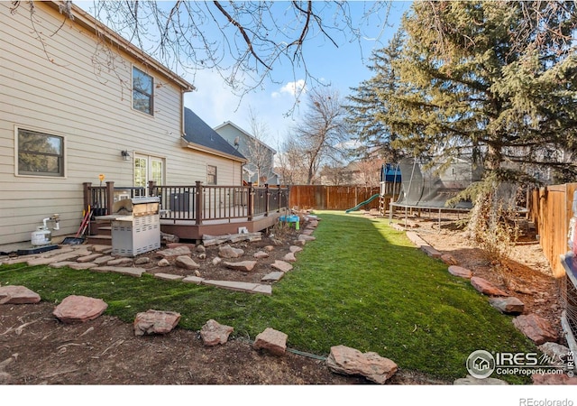 view of yard featuring a trampoline, a wooden deck, and a playground