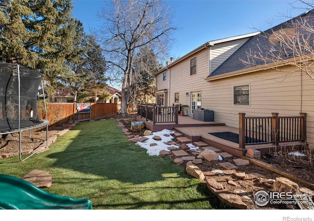 view of yard with a trampoline, a wooden deck, and central air condition unit