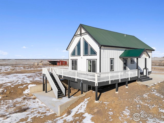 snow covered back of property with a wooden deck