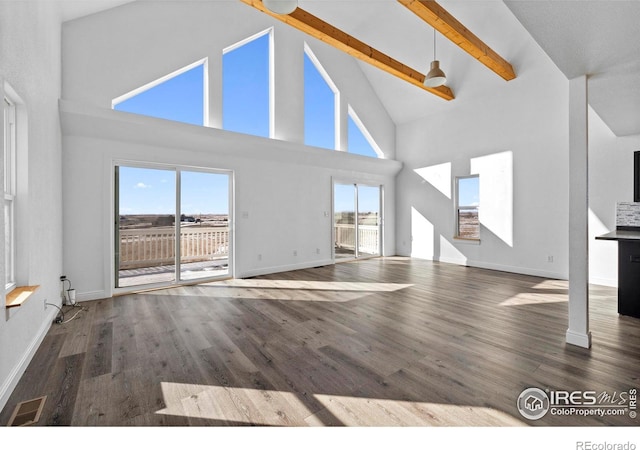 unfurnished living room with beamed ceiling, dark hardwood / wood-style flooring, and high vaulted ceiling