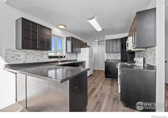 kitchen with white appliances, a textured ceiling, light hardwood / wood-style floors, sink, and kitchen peninsula