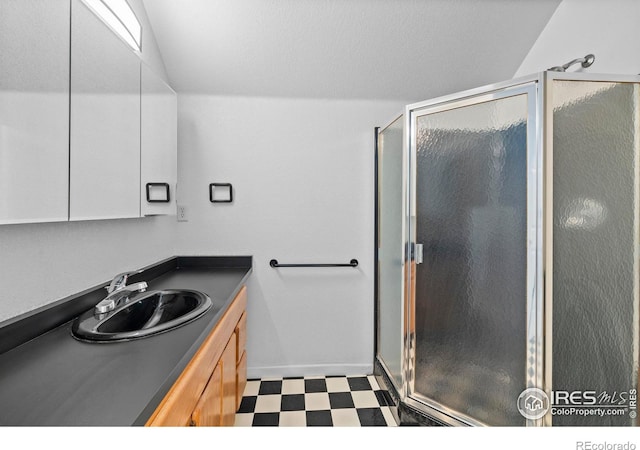 bathroom featuring a shower with door and vanity