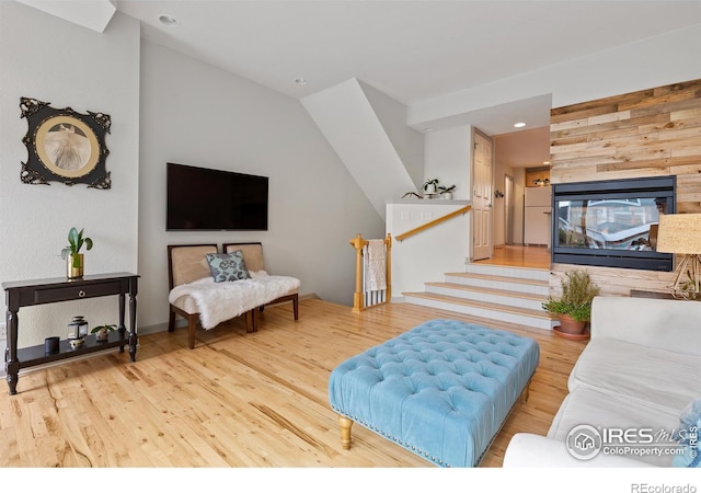 living room with vaulted ceiling, a multi sided fireplace, and light hardwood / wood-style flooring