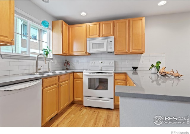 kitchen with sink, light wood-type flooring, white appliances, and tasteful backsplash