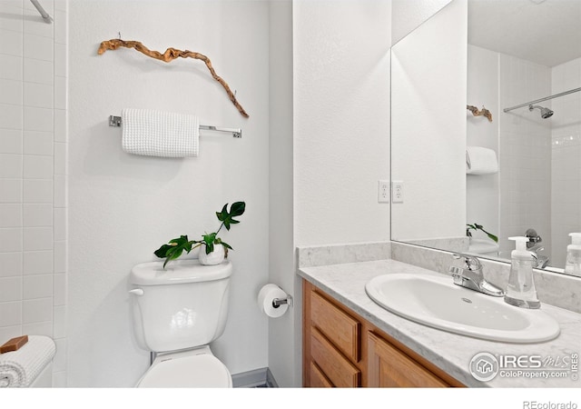 bathroom featuring vanity, toilet, and a tile shower