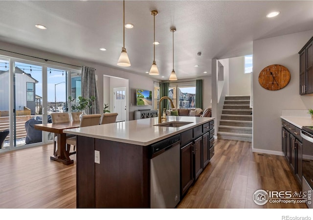 kitchen with dark brown cabinetry, sink, decorative light fixtures, a center island with sink, and dishwasher