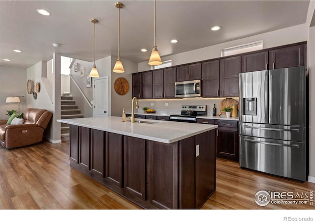 kitchen featuring appliances with stainless steel finishes, sink, dark brown cabinets, and decorative light fixtures