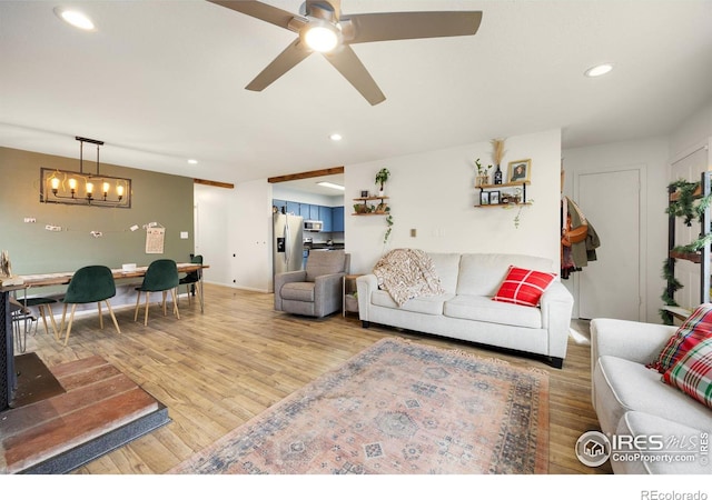 living room featuring light hardwood / wood-style floors and ceiling fan with notable chandelier