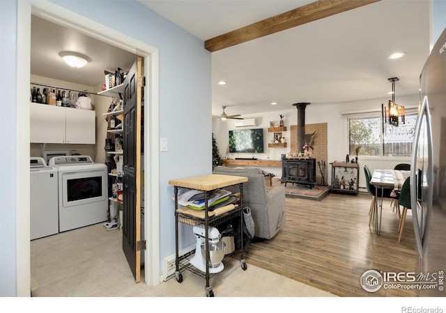 kitchen featuring beamed ceiling, white cabinetry, decorative light fixtures, a wood stove, and washer and dryer