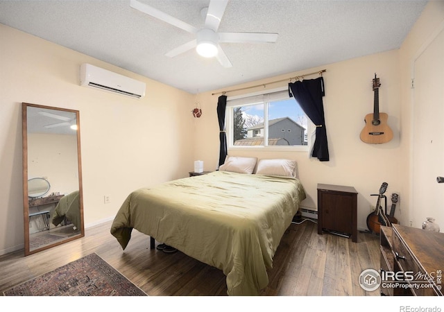 bedroom featuring a textured ceiling, wood-type flooring, a baseboard heating unit, ceiling fan, and a wall mounted AC