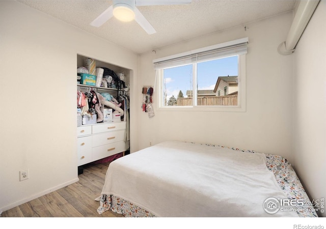 bedroom with ceiling fan, light hardwood / wood-style floors, a textured ceiling, and a closet