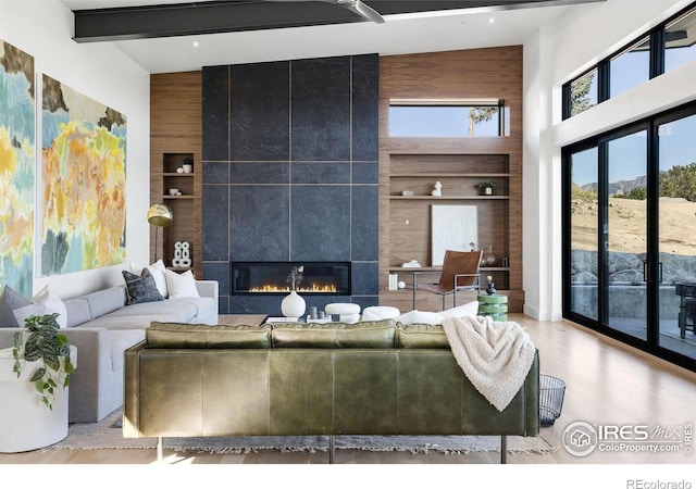 living room with built in features, a tile fireplace, high vaulted ceiling, wooden walls, and beamed ceiling