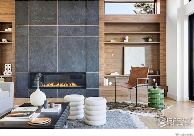 living room featuring built in shelves, a tile fireplace, and wooden walls