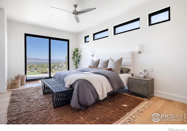 bedroom featuring wood-type flooring, a mountain view, and ceiling fan