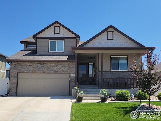 view of front of home featuring a garage, covered porch, and a front yard