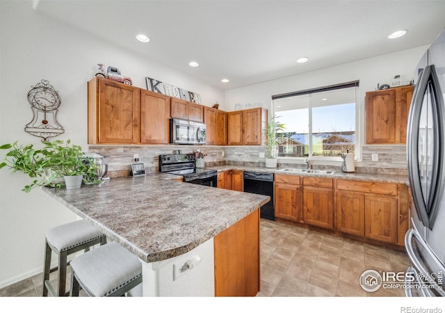 kitchen with kitchen peninsula, backsplash, black appliances, and a breakfast bar area