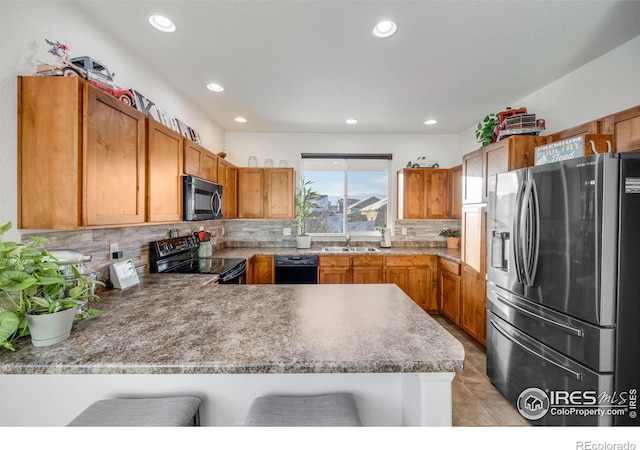 kitchen featuring black appliances, a kitchen breakfast bar, backsplash, sink, and kitchen peninsula