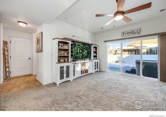 unfurnished living room with ceiling fan and carpet