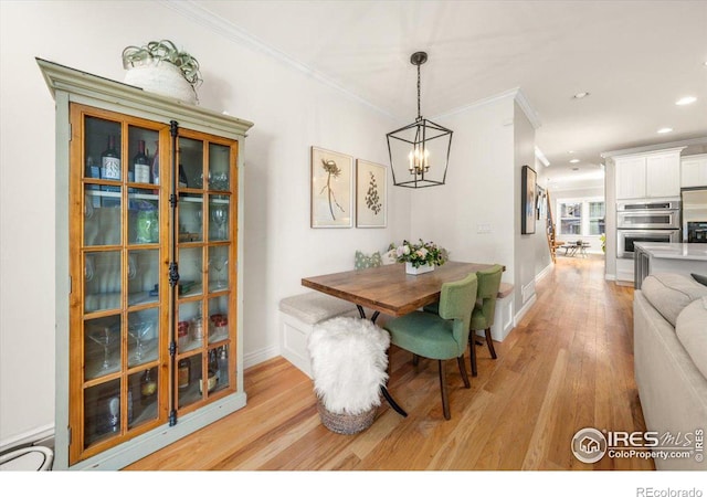 dining room featuring light wood-type flooring, a chandelier, and ornamental molding