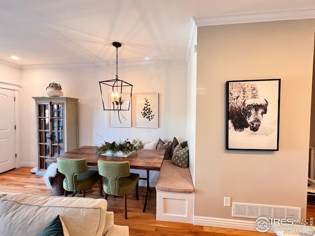 dining area featuring hardwood / wood-style flooring, ornamental molding, and a chandelier