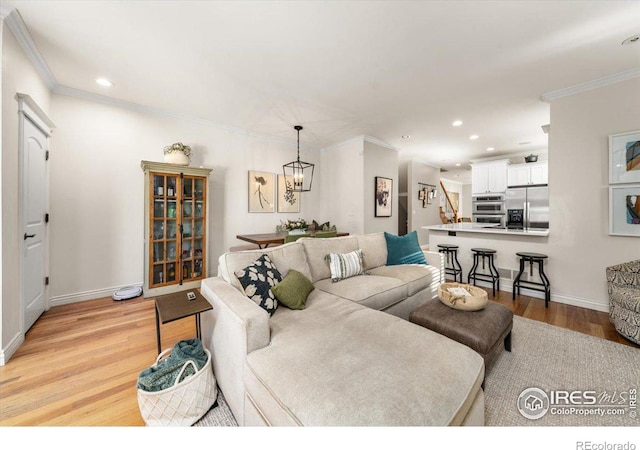 living room featuring crown molding, light hardwood / wood-style floors, and a notable chandelier