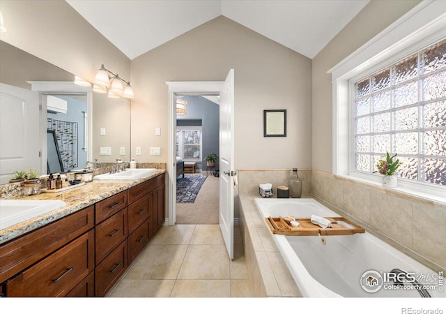 bathroom with vanity, vaulted ceiling, tiled tub, and tile patterned flooring