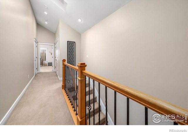 hallway featuring vaulted ceiling and light colored carpet