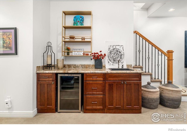 bar featuring light stone counters, light colored carpet, sink, and wine cooler